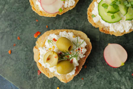 Tasty sandwich with cottage cheese and olives on color backgroundの写真素材