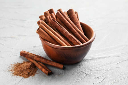 Cinnamon sticks in bowl on gray backgroundの写真素材