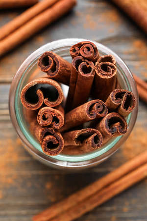 Cinnamon sticks in jar on wooden background