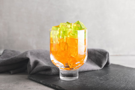 Glass with tasty jelly cubes on grunge background
