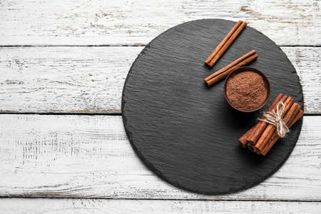 Cinnamon sticks and bowl with powder on wooden backgroundの写真素材