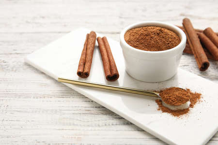 Cinnamon sticks and bowl with powder on wooden backgroundの写真素材