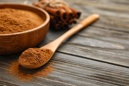 Bowl and spoon with cinnamon powder on wooden backgroundの写真素材