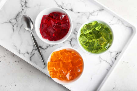 Bowls with tasty jelly cubes on trayの写真素材