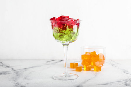 Glass with tasty jelly cubes on white backgroundの写真素材