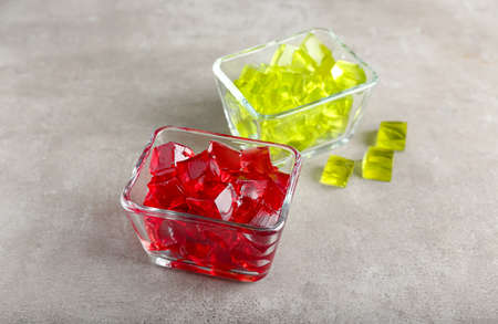 Glass bowls with tasty jelly cubes on grunge backgroundの写真素材
