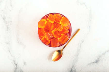 Glass with tasty jelly cubes on white backgroundの写真素材