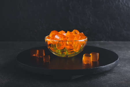 Glass bowl with tasty jelly cubes on dark backgroundの写真素材
