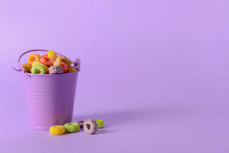 Small bucket with crunchy corn flakes rings on color backgroundの写真素材