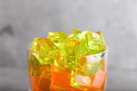 Glass with tasty jelly cubes on grunge background, closeupの写真素材