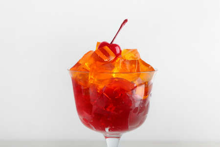 Glass with tasty jelly cubes on white backgroundの写真素材