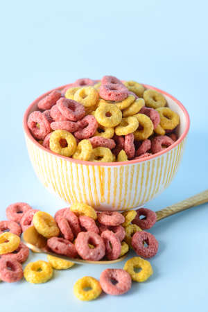 Bowl and spoon with crunchy corn flakes rings on color backgroundの写真素材