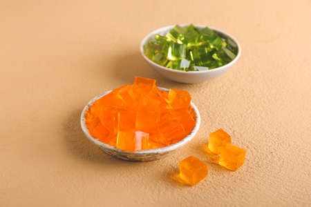 Plates with tasty jelly cubes on color backgroundの写真素材