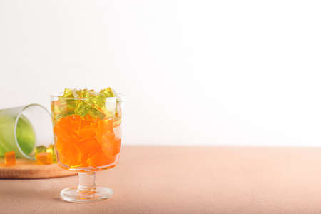Glass with tasty jelly cubes on tableの写真素材