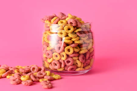 Glass with crunchy corn flakes rings on color backgroundの写真素材
