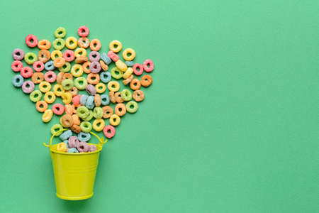 Small bucket with crunchy corn flakes rings on color backgroundの写真素材