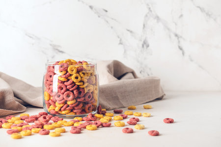 Glass with crunchy corn flakes rings on white background