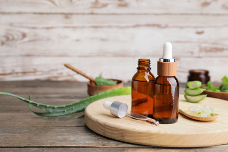 Bottles of essential oil and spoon with aloe on wooden backgroundの写真素材