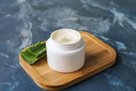 Jar with natural cream and aloe leaves on color backgroundの写真素材