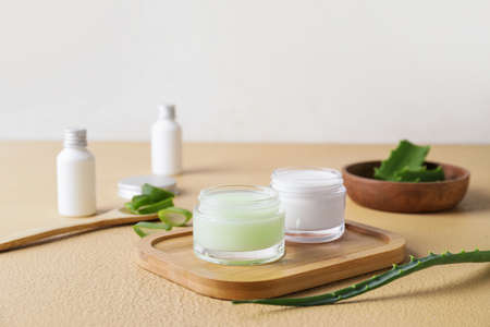 Jar with natural cream and aloe leaves on color backgroundの写真素材