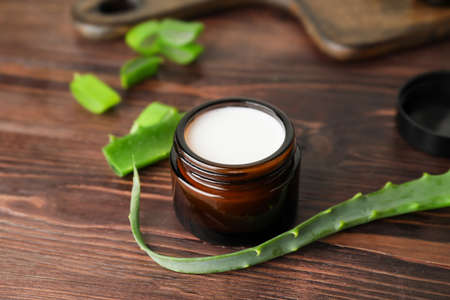 Jar with natural cream and aloe pieces on wooden backgroundの写真素材
