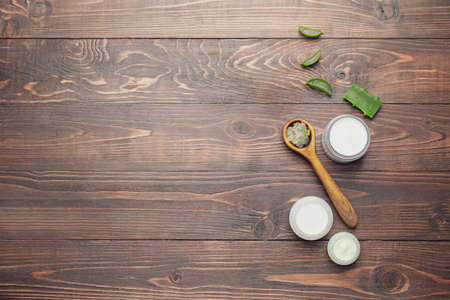 Jars of natural cream and spoon with aloe pieces on wooden backgroundの写真素材
