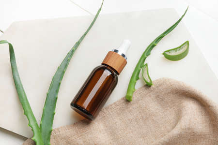 Bottle of essential oil and aloe leaves on light wooden backgroundの写真素材