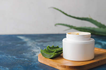 Jar with natural cream and aloe leaves on color backgroundの写真素材