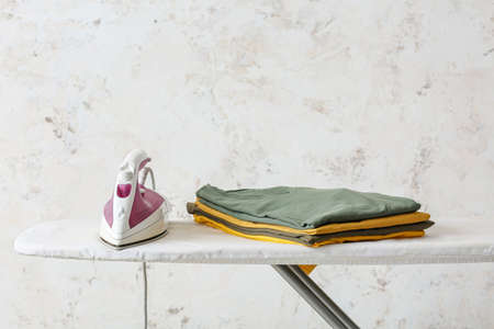 Electric iron and board on light background