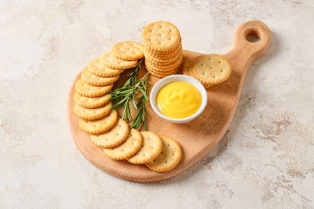 Board with tasty crackers on light background