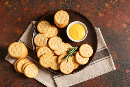 Plate with tasty crackers on grunge backgroundの写真素材