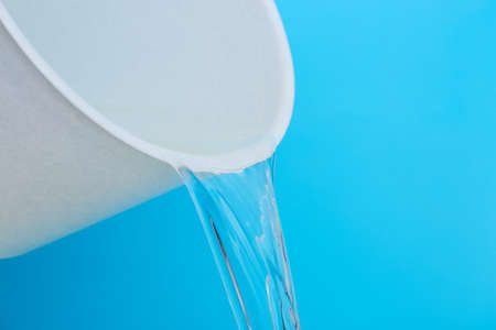 Pouring of water from bucket on color background, closeupの写真素材