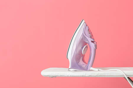 Electric iron and board on color backgroundの写真素材