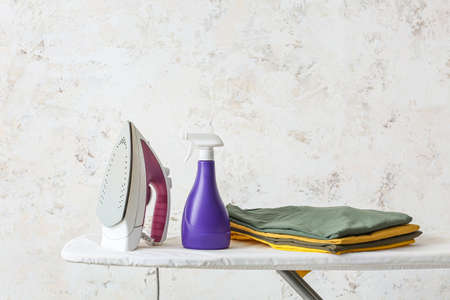 Electric iron and board on light background