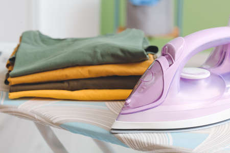 Board with electric iron and clean clothes, closeupの写真素材