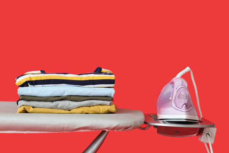 Board with electric iron and clean clothes on color backgroundの写真素材