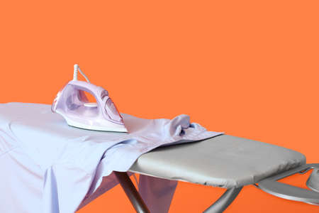 Board with electric iron and clean cloth on color backgroundの写真素材