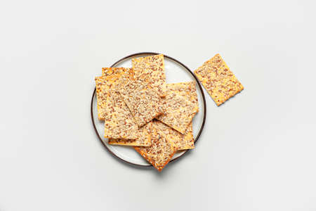Tasty crackers with seeds in plate on white backgroundの写真素材