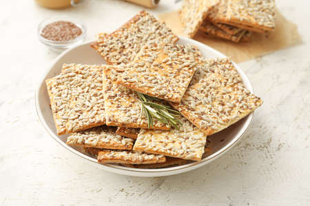 Tasty crackers with seeds in plate on light backgroundの写真素材