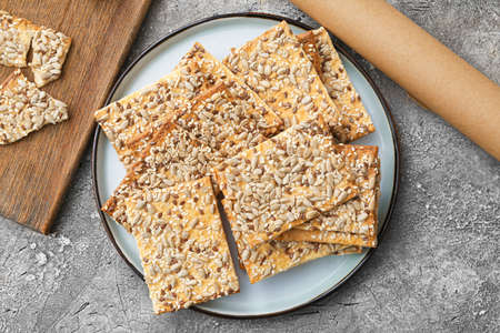 Tasty crackers with seeds in plate on gray backgroundの写真素材