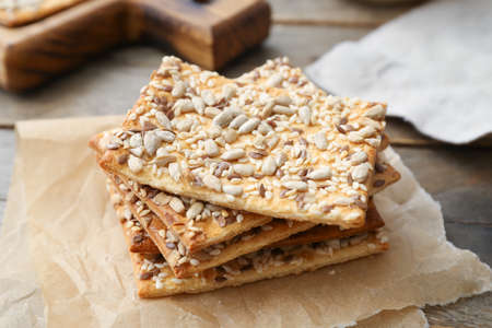 Tasty crackers with seeds on wooden background, closeup