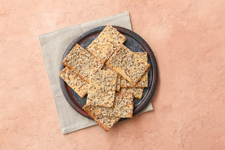 Tasty crackers with seeds in plate on color backgroundの写真素材