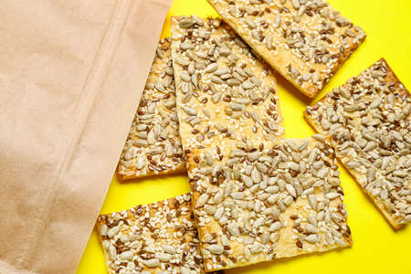 Tasty crackers with seeds in bag on color backgroundの写真素材