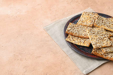 Tasty crackers with seeds in plate on color backgroundの写真素材