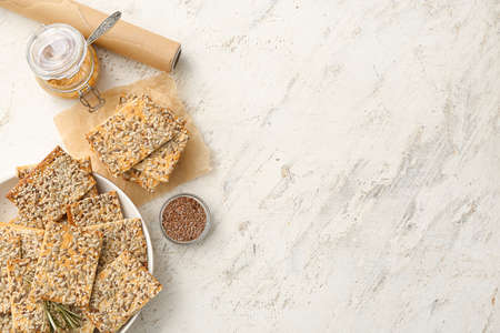 Tasty crackers with seeds in plate on light backgroundの写真素材