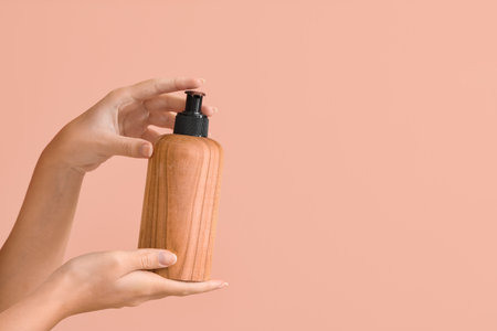 Female hands with natural cosmetic product in bottle on color backgroundの写真素材