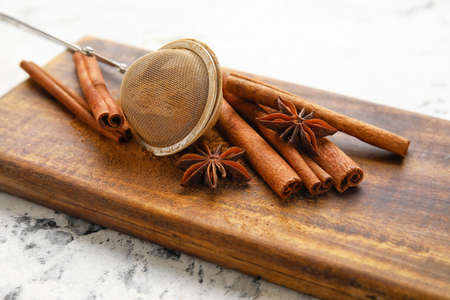 Tea strainer and aromatic cinnamon on tableの写真素材