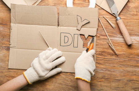 Woman carving word DIY made of cardboard on wooden backgroundの写真素材