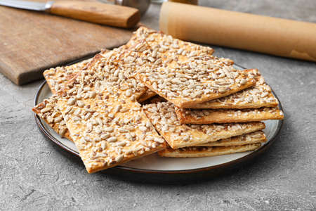 Tasty crackers with seeds in plate on gray backgroundの写真素材