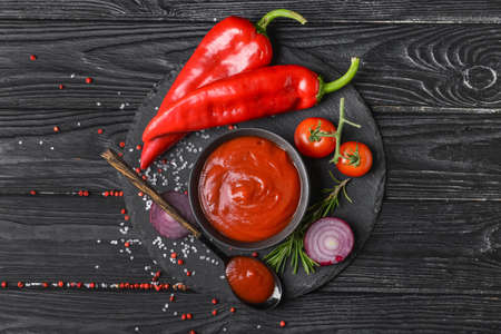 Bowl with organic tomato sauce and ingredients on dark wooden backgroundの写真素材
